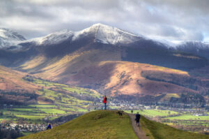 walking in cumbria. view of local mountainsides with hiker