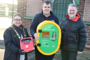 Millom’s Town Mayor and Chair of Council receiving a defibrillator kindly donated by J F Hornby & Co